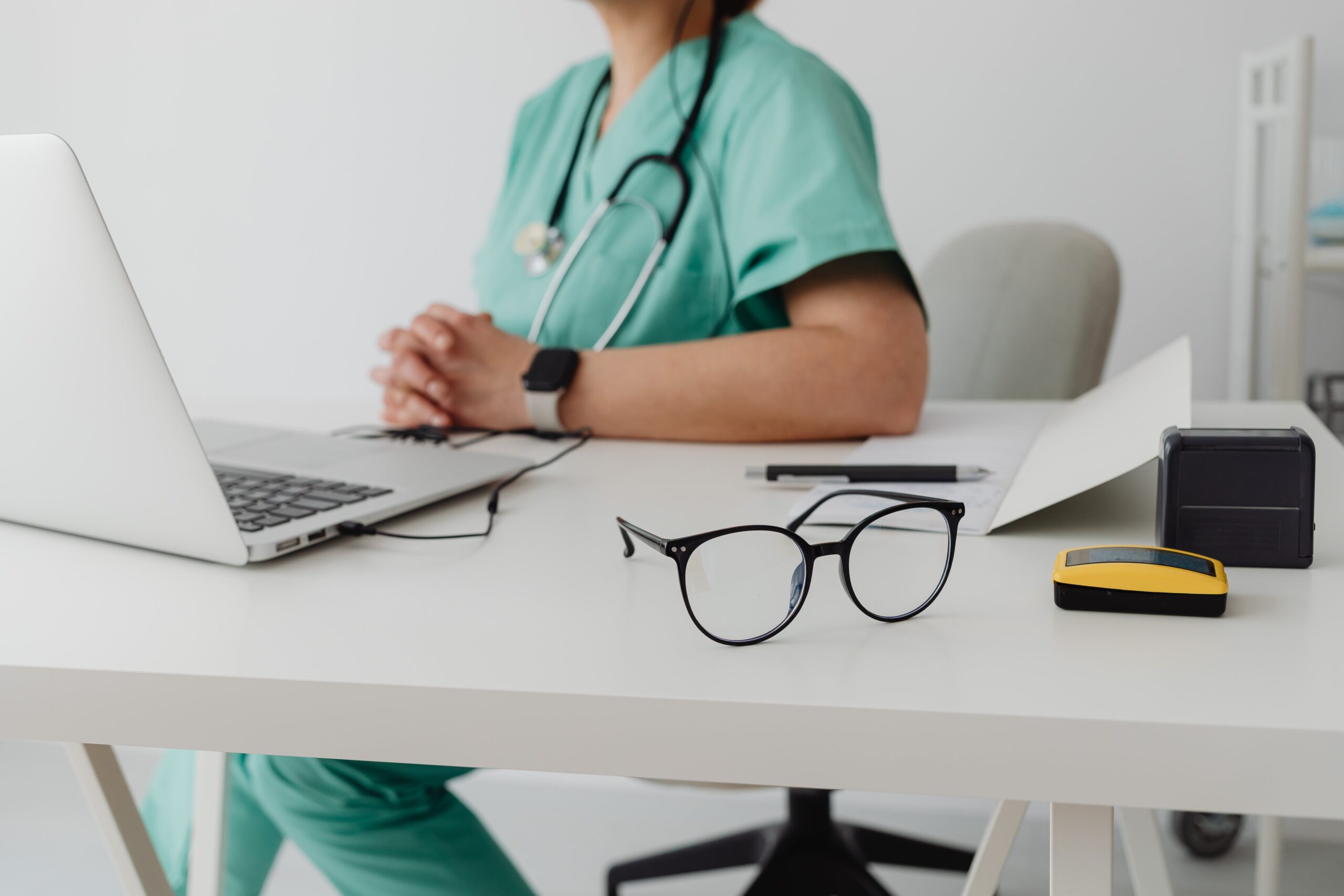 woman in blue scrub suit using MacBook Pro