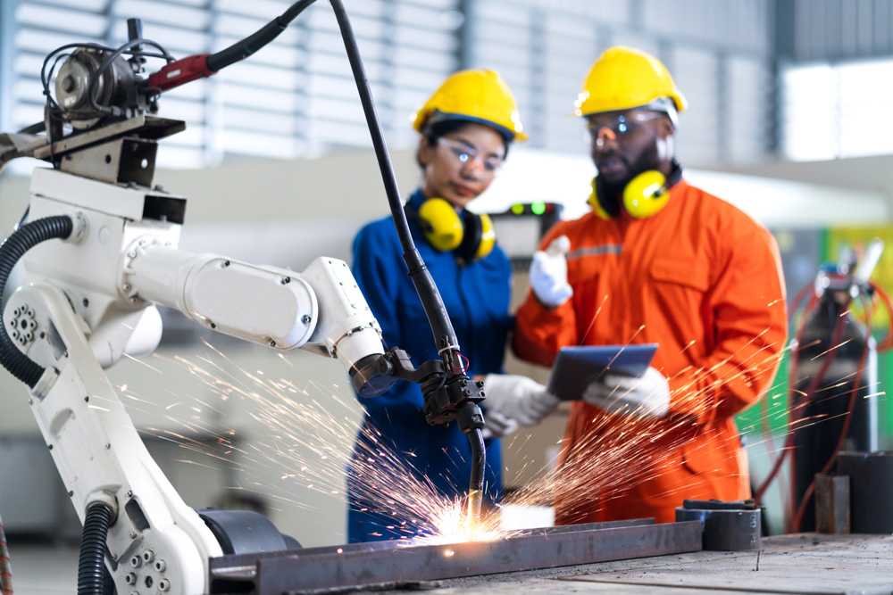 A welding robot controlled by two technicians