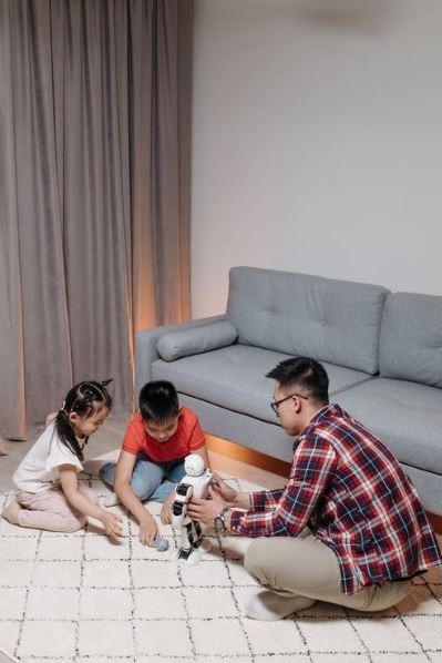 A man playing with his kids while holding the robot