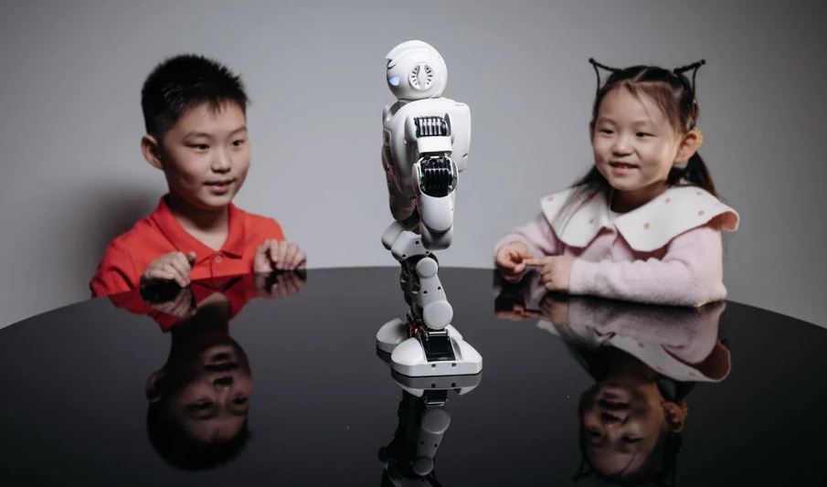 a young girl and boy looking at the robot