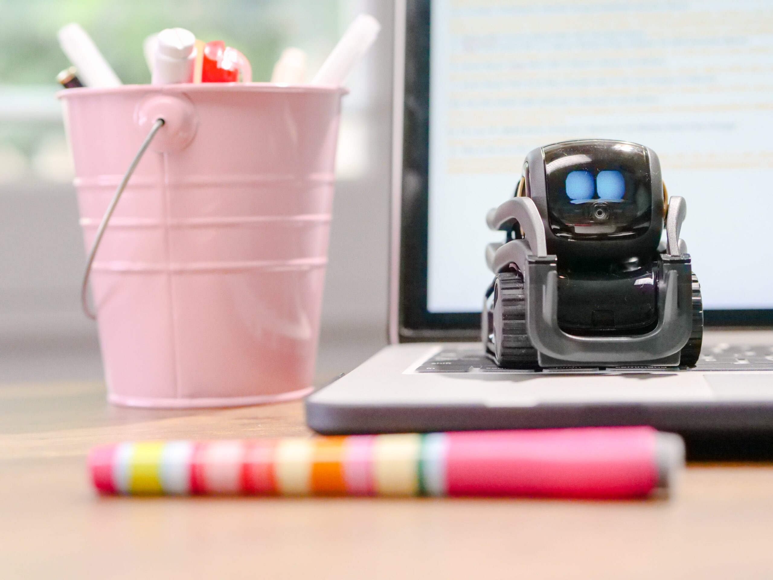 miniature toy robot on top of laptop keyboard